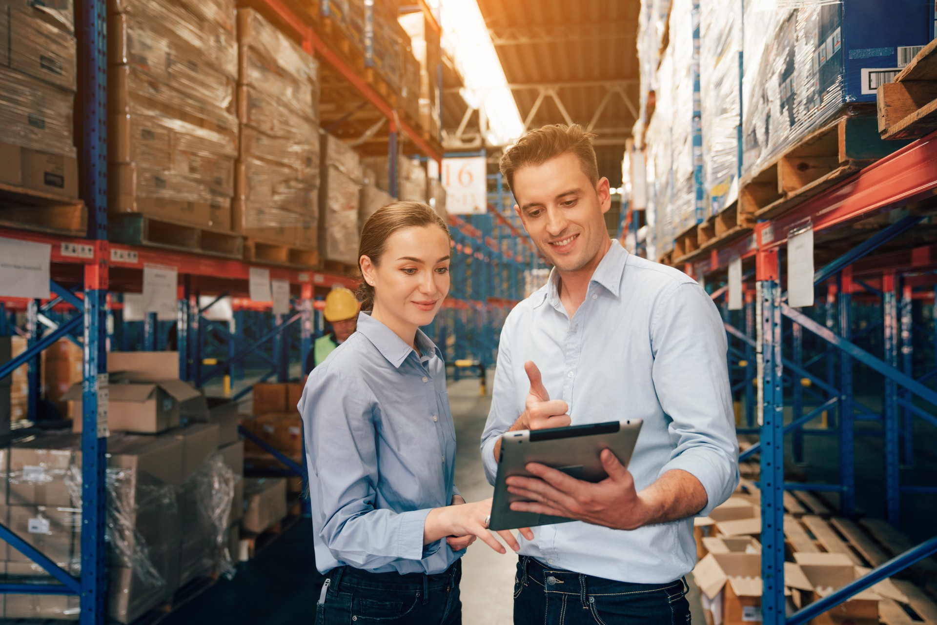 Warehouse manager talking and using digital tablet while checking product in warehouse.